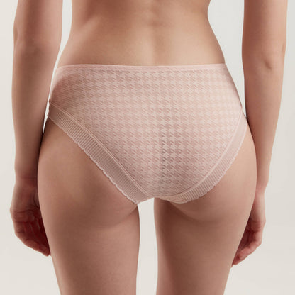 A back view of a person wearing light pink, low-rise briefs featuring a subtle houndstooth pattern and delicate lace trim along the leg openings.