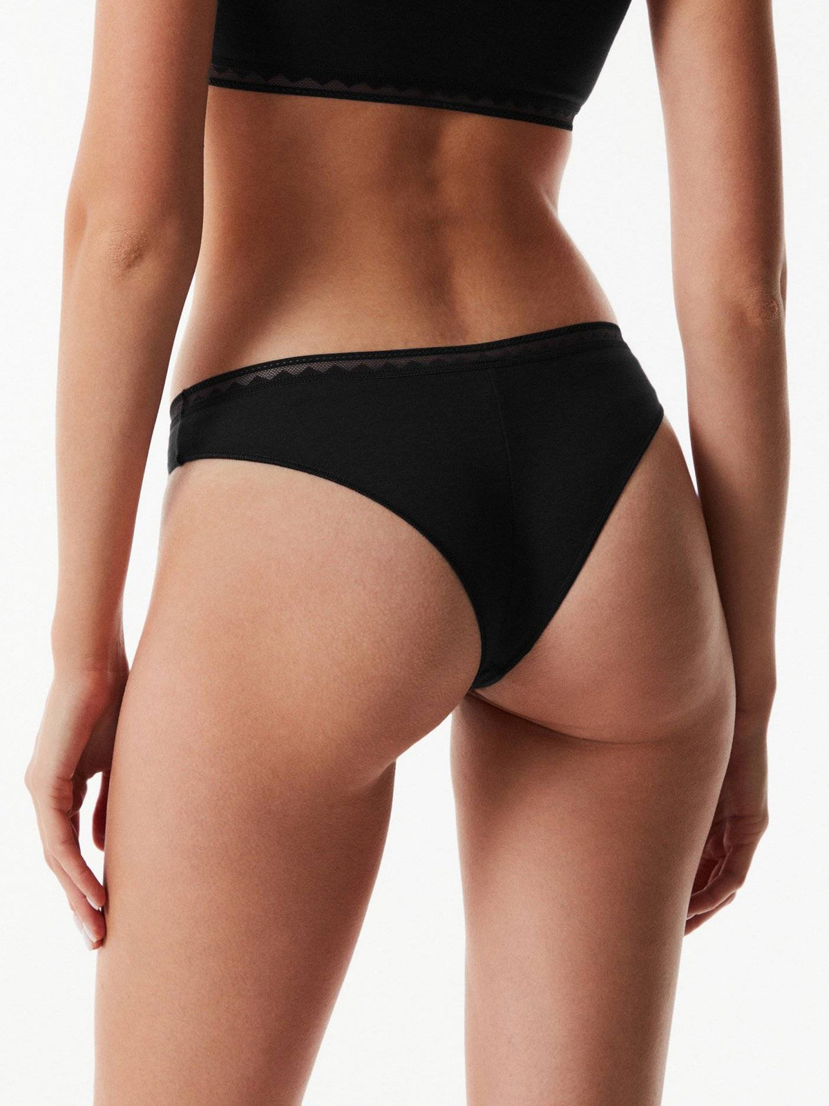Black bikini-style panties viewed from behind on a person against a plain white background.