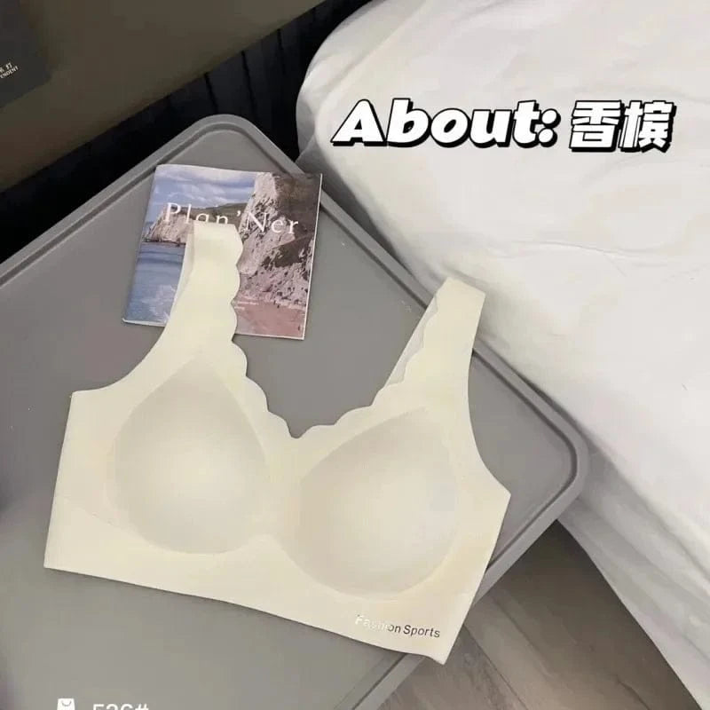 A beige wireless scalloped-edge sports bra is laid flat on a grey tray next to a small notebook.