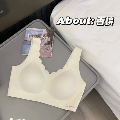 A beige wireless scalloped-edge sports bra is laid flat on a grey tray next to a small notebook.