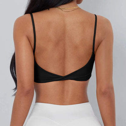 A black cropped camisole with thin spaghetti straps and a low-cut back featuring a twisted hem detail, worn by a person with long dark hair.