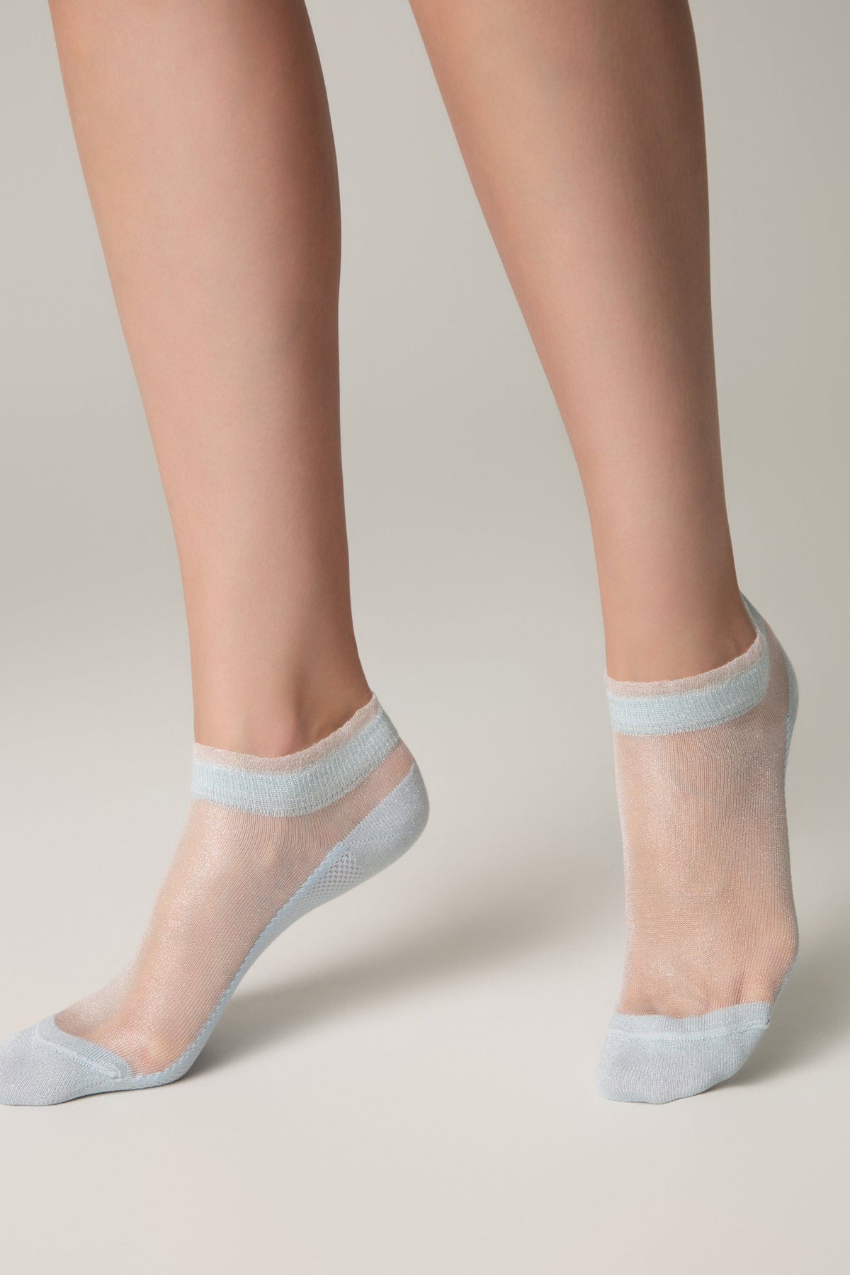 Sheer ankle socks in a shimmering light blue color worn on a person's feet against a plain background.