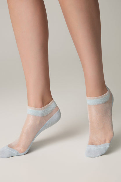 Sheer ankle socks in a shimmering light blue color worn on a person's feet against a plain background.