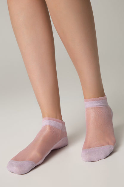 A pair of sheer light purple ankle socks worn on a person's feet against a plain light gray background.