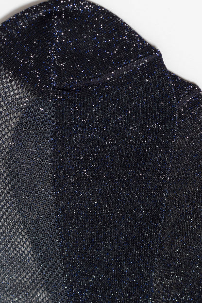 A close-up of a dark navy blue knit top featuring a shimmery, metallic finish and a subtle semi-sheer mesh texture along the left side.