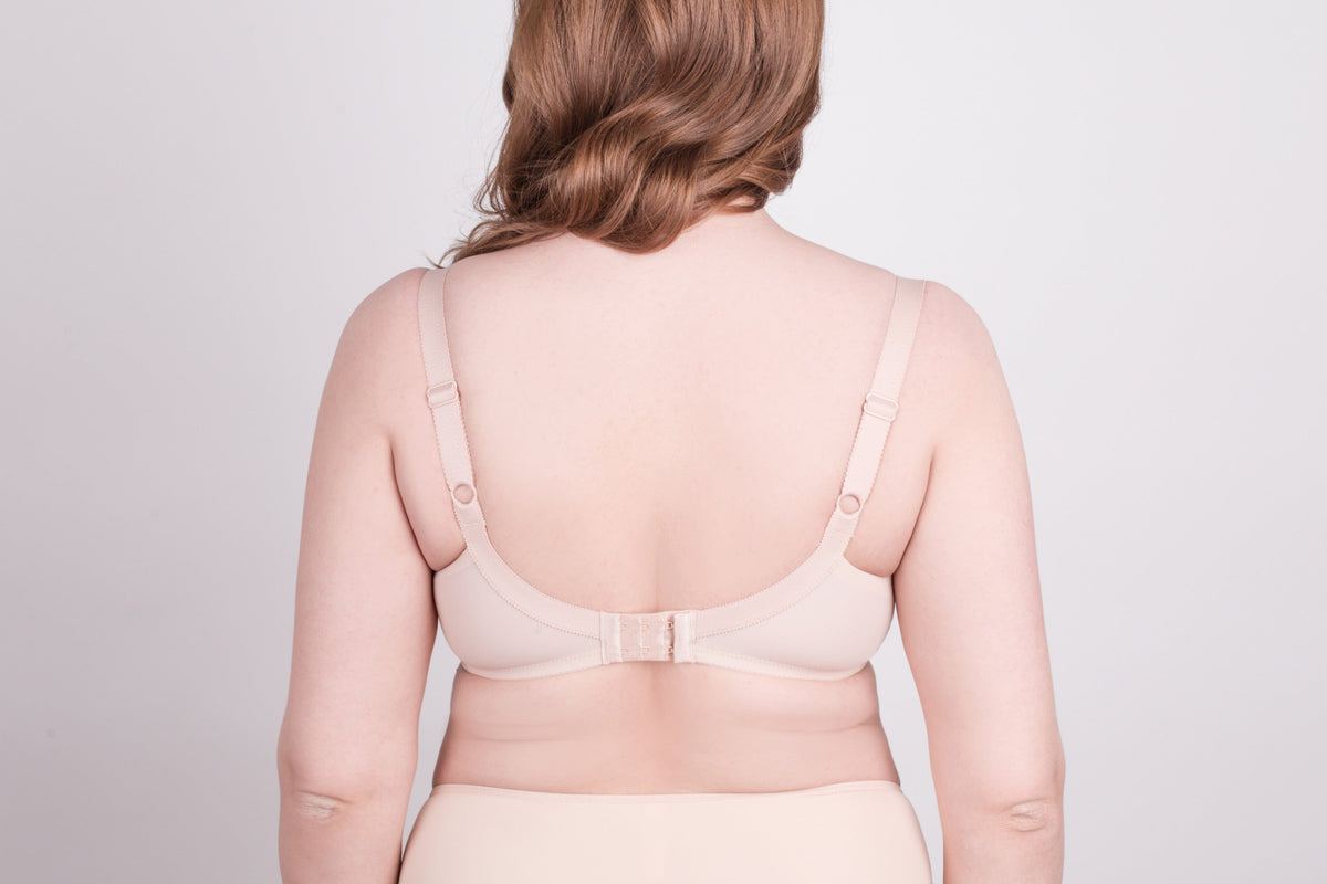A beige bra shown from the back view on a person with fair skin against a light grey background.