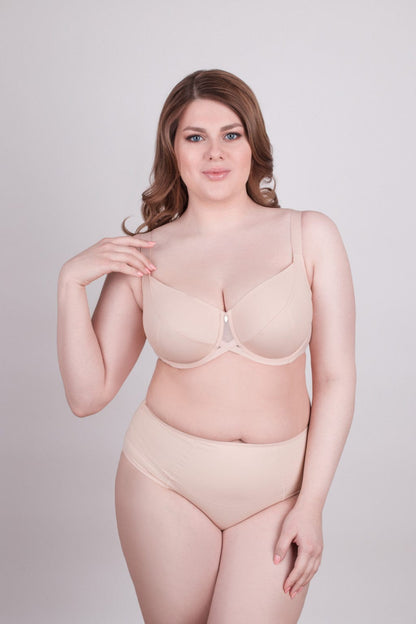 A beige underwire bra and matching high-waisted briefs worn by a woman against a plain grey background.