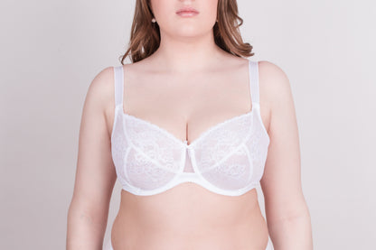 A white lace underwire bra with wide shoulder straps is worn by a woman against a light grey background.