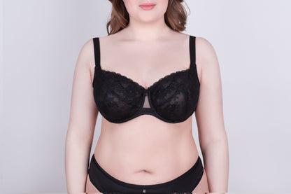 A black lace bra with adjustable straps worn by a person against a plain light gray background.