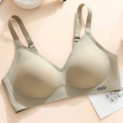 A beige ribbed wireless bralette with adjustable shoulder straps and a small metal Smile charm on the front band, displayed on a light background.