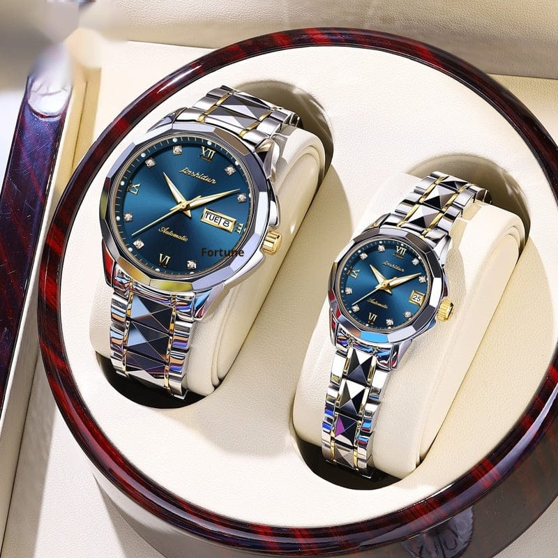 A pair of matching wristwatches with blue dials, silver and gold-tone metal links, and diamond-style indices are displayed inside a rounded, wood-grain patterned gift box.