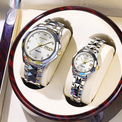 A pair of silver and gold-toned automatic watches with diamond-accented indices and patterned links, displayed inside a circular brown wooden gift box.
