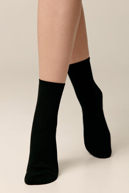 A pair of black crew socks worn on a person's legs against a neutral background.