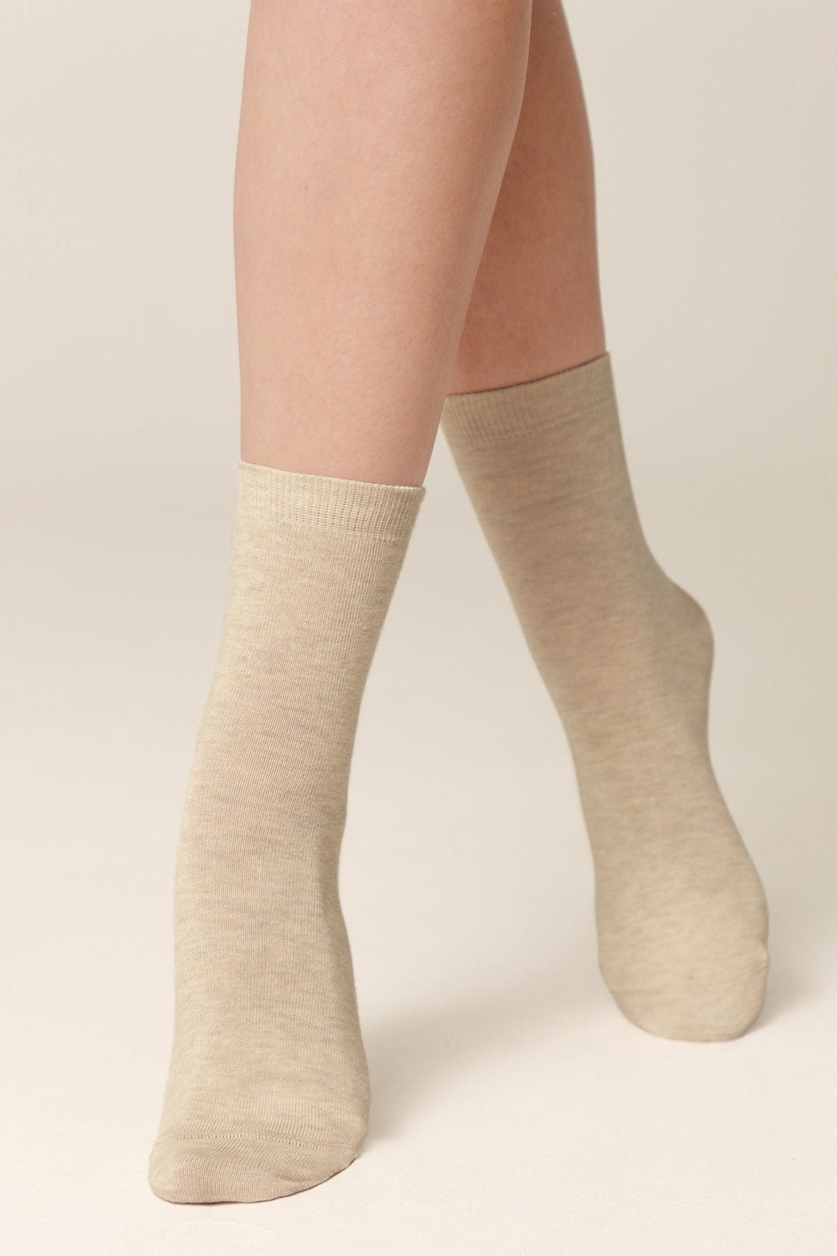 Beige crew socks worn on a person's feet against a neutral background.