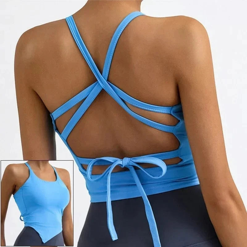 A light blue cropped athletic tank top features a strappy, crisscross open-back design with a tie closure, shown from both the front and back views against a plain background.