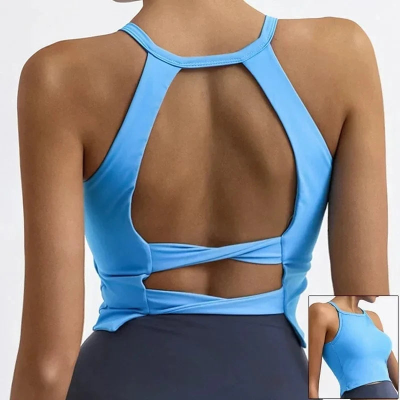 A bright blue sleeveless athletic crop top features a high neckline and a cutout back design with a horizontal strap detail against a dark grey waistband.