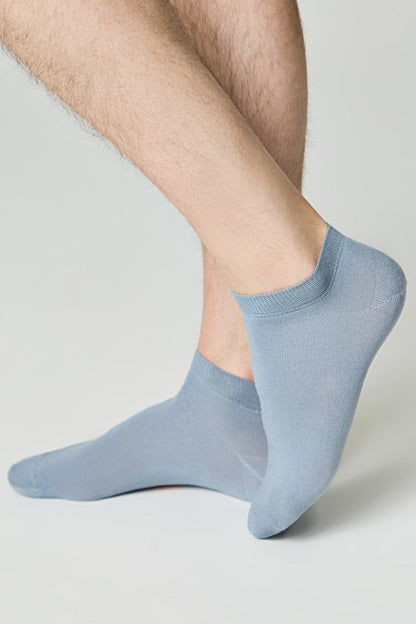 Light blue low-cut ankle socks worn on a person's feet against a plain light gray background.