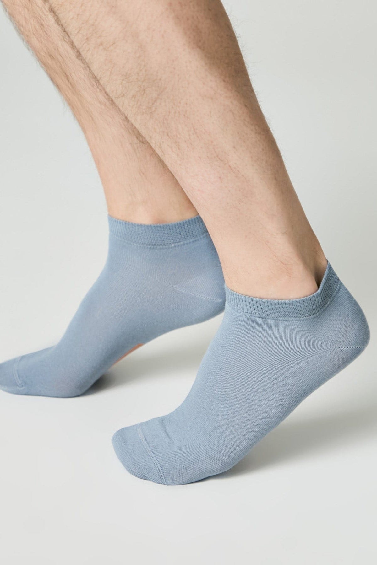 A pair of light blue ankle socks worn on a person's feet against a plain white background.