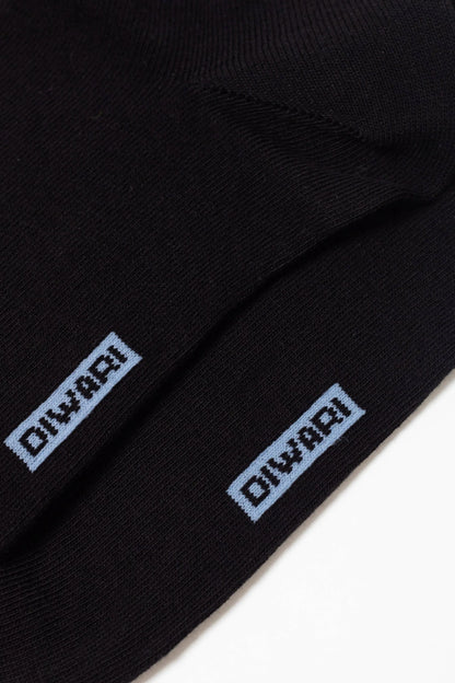 A pair of black socks features a light blue rectangular logo with the word DIWARI embroidered on the side.