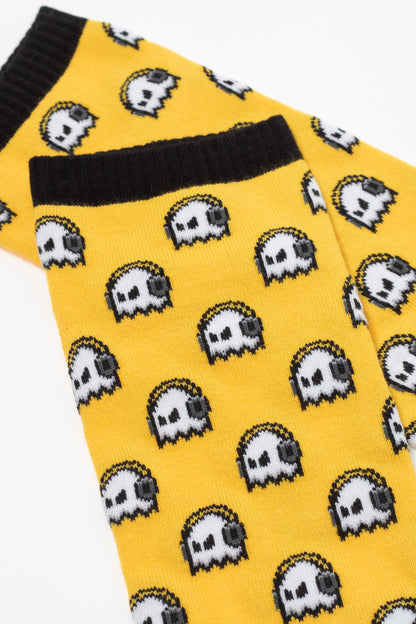 A pair of yellow socks featuring a repeating pattern of white and grey pixelated ghost characters with black outlines and black cuffs at the top.