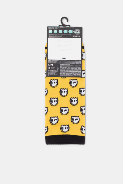 A pair of yellow crew socks featuring a repeating pattern of white and black cartoon-style faces, with a black cuff and toe area and a tag attached at the top.