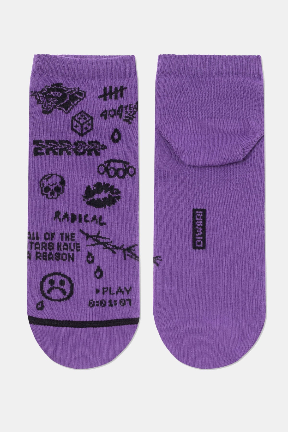 A pair of purple ankle socks feature a black graphic pattern on the left sock, including a skull, a sad face, the word RADICAL, and various small symbols, while the right sock is solid purple with a small black rectangular logo on the heel.