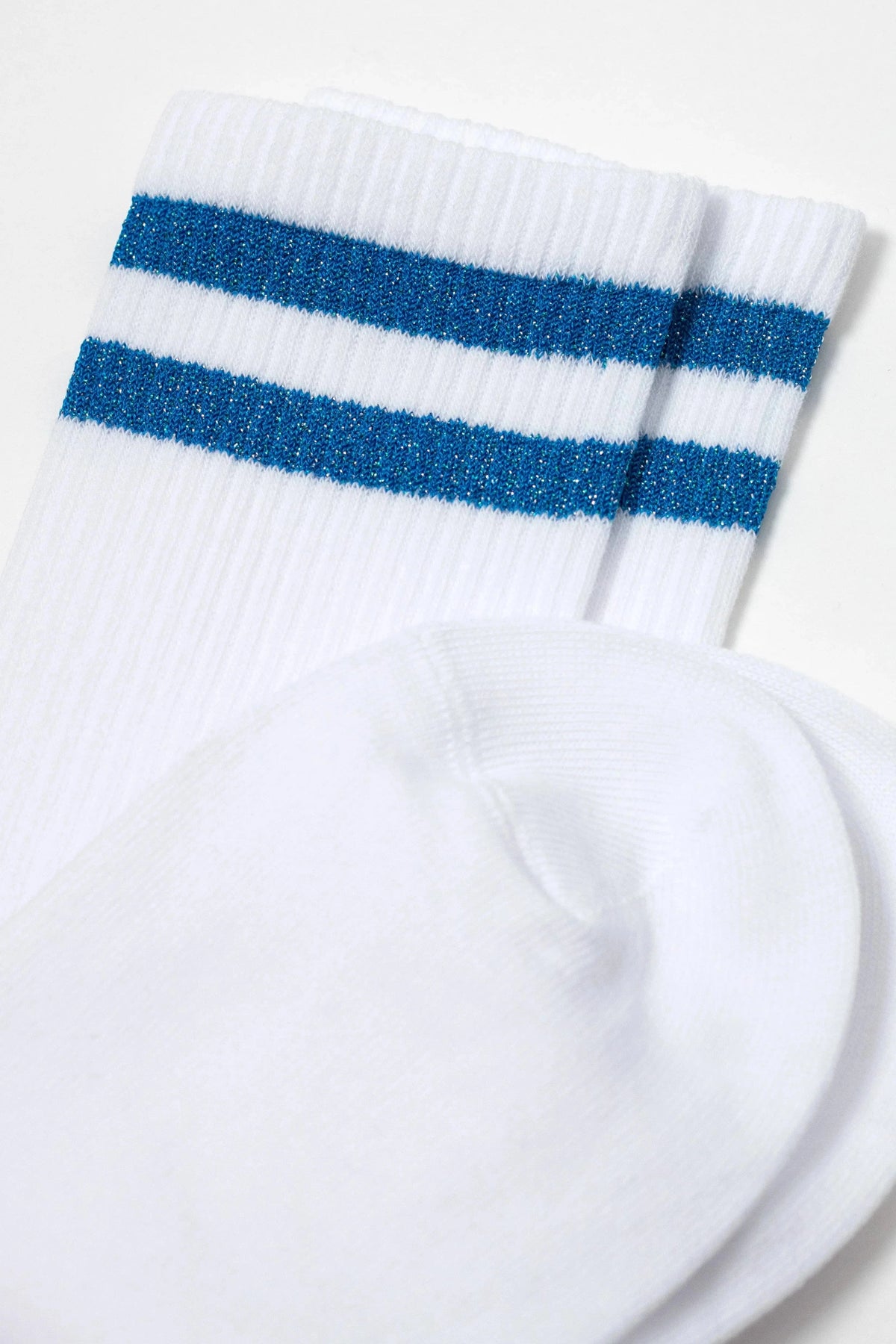 A pair of white crew-length socks featuring two horizontal metallic blue stripes near the ribbed cuffs.
