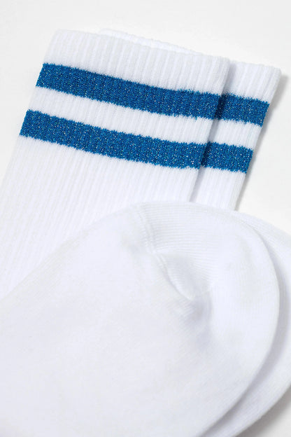 A pair of white crew-length socks featuring two horizontal metallic blue stripes near the ribbed cuffs.