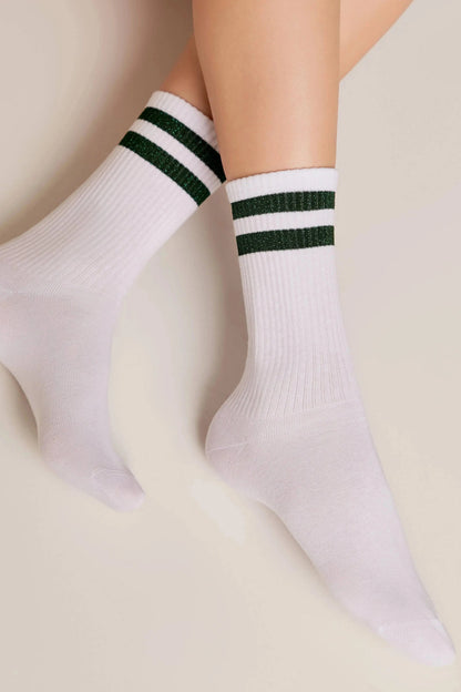 A pair of white crew socks featuring two horizontal dark green glittery stripes around the ribbed cuffs on the legs.