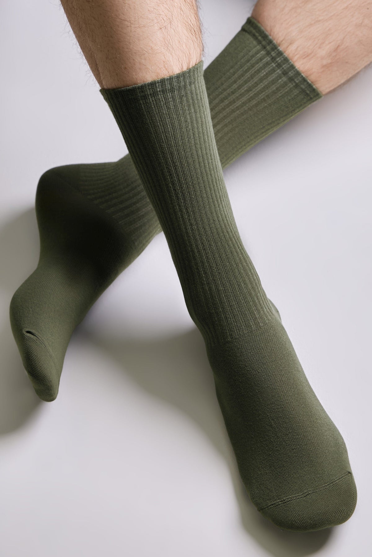 Olive green crew socks worn on a person's feet against a plain white background.