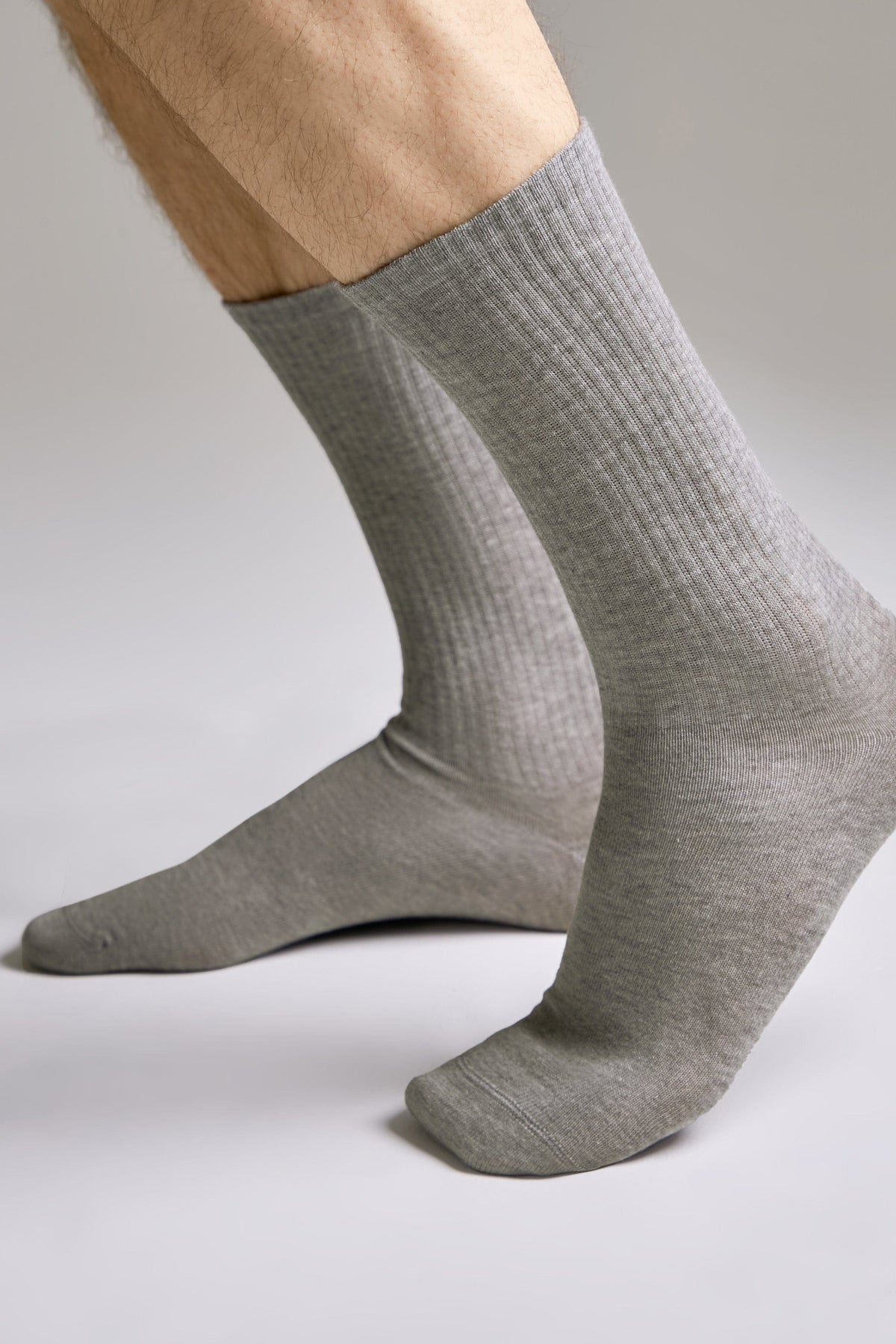 A pair of mid-calf grey ribbed socks worn on a person's feet against a plain light background.