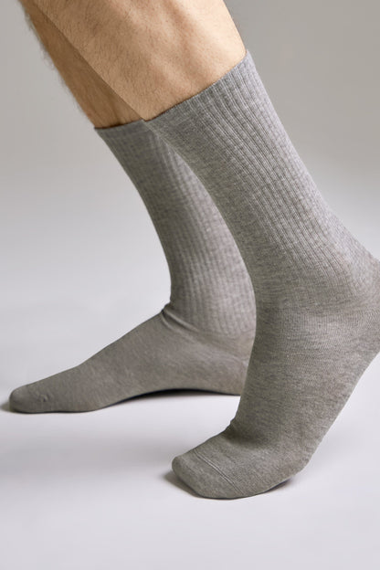 A pair of mid-calf grey ribbed socks worn on a person's feet against a plain light background.