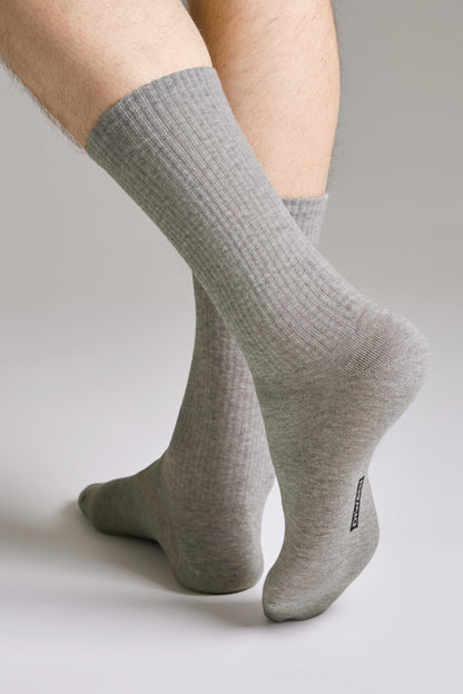 A pair of light grey ribbed crew-length socks worn on a person's feet against a plain light background.