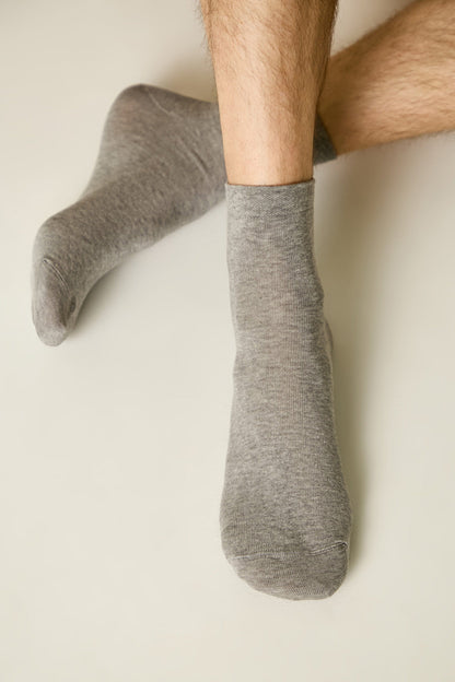 A pair of grey crew socks worn on a person's feet against a neutral background.