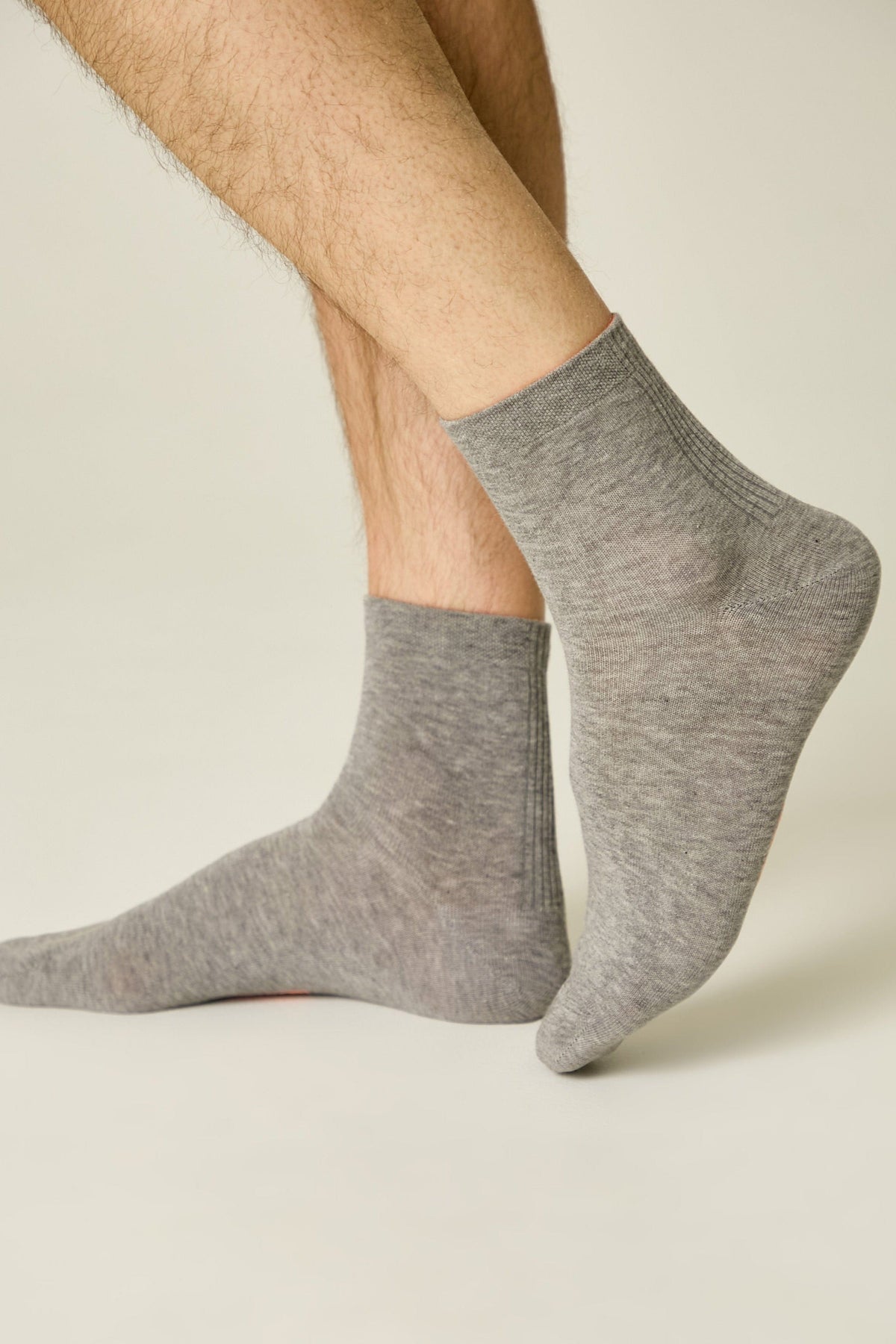 A pair of grey ankle socks worn on a person's feet against a light background.
