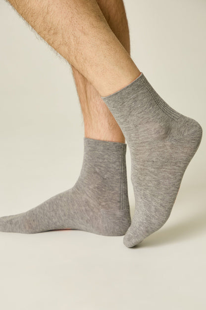 A pair of grey ankle socks worn on a person's feet against a light background.