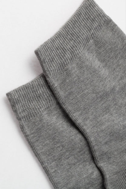 A pair of plain gray socks are folded flat, showcasing the ribbed knit cuffs and the fine, consistent texture of the fabric.
