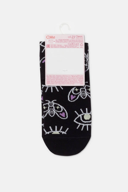 A pair of folded black socks decorated with a repeating pattern of white and purple moths and open eyes, hanging from a branded paper display tag.