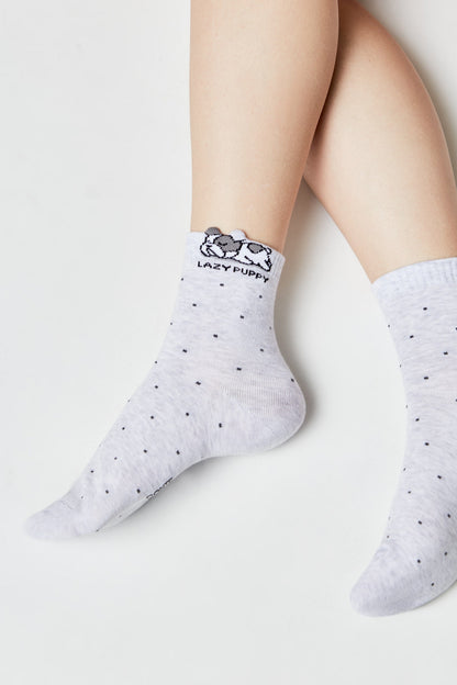 A pair of light grey ankle socks featuring a subtle pattern of tiny dark dots and a graphic of a resting puppy with the words LAZY PUPPY embroidered at the top.