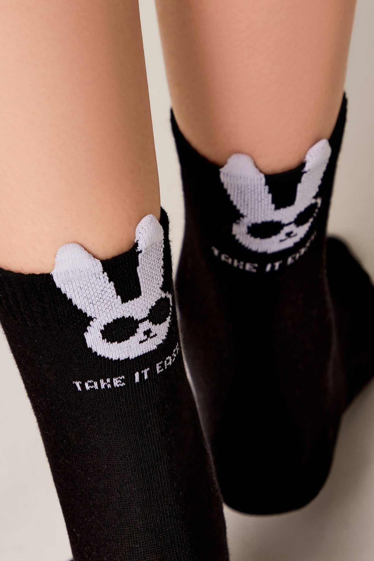 Black socks featuring a white cartoon rabbit wearing sunglasses and the text "TAKE IT EASY" on the cuffs.