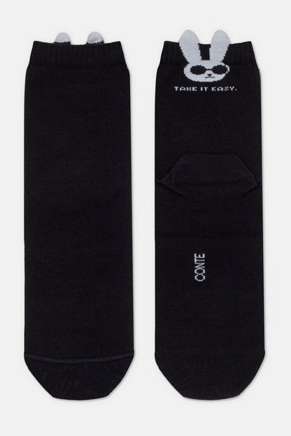 A pair of black ankle socks featuring a white bunny character wearing sunglasses and the text "TAKE IT EASY" printed at the top, with small grey 3D ears extending from the cuffs.