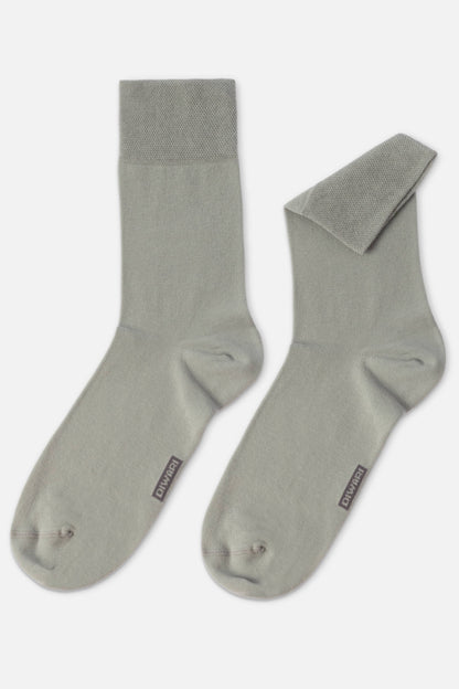 A pair of sage green crew socks with a textured cuff and a small logo tag on the side of each foot.
