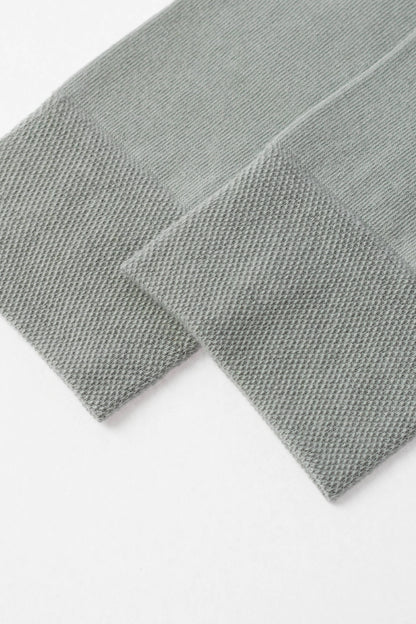 A pair of folded sage green socks with ribbed cuffs shown against a plain white background.