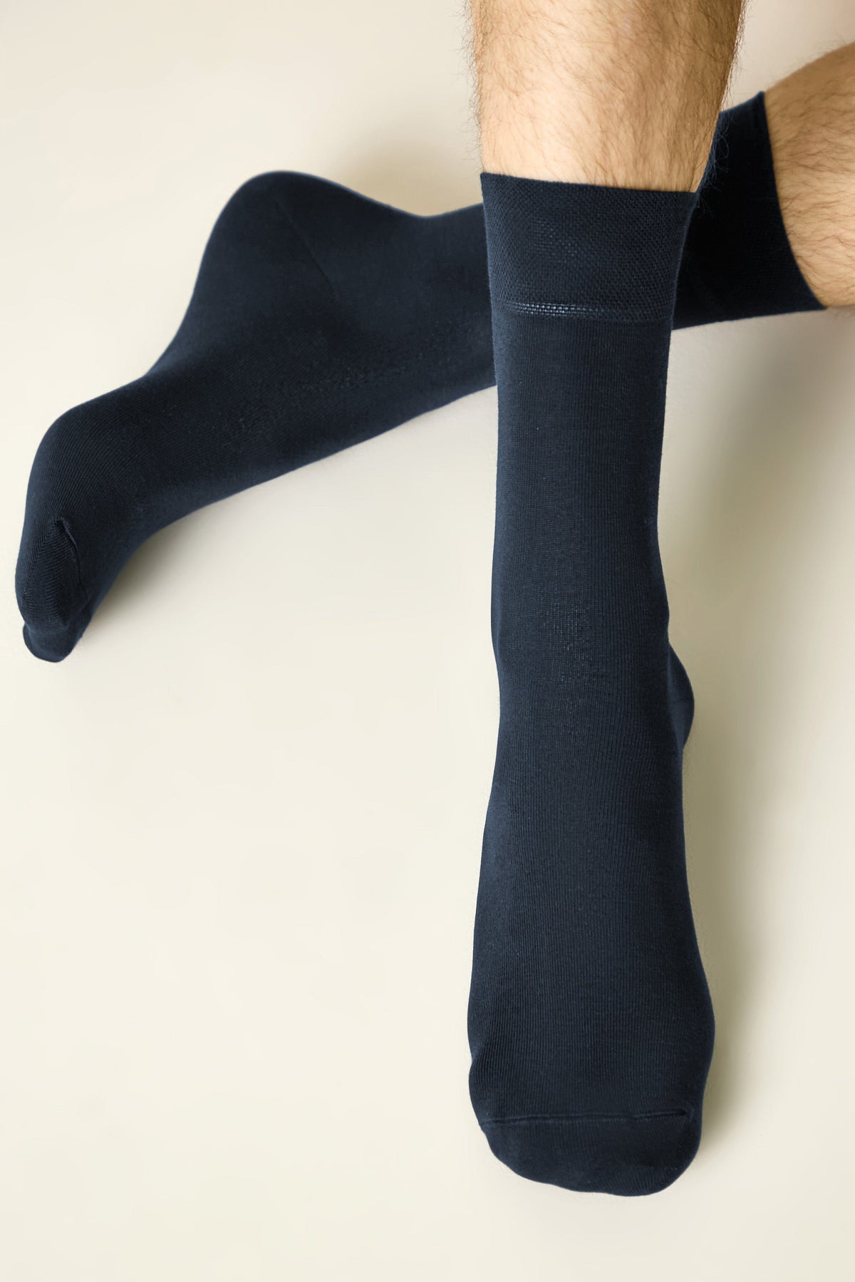 A pair of dark navy blue mid-calf socks worn on a person's legs against a plain light background.
