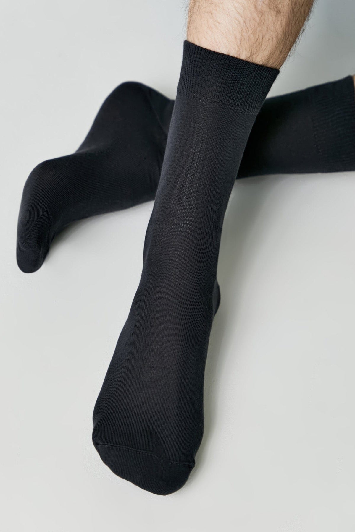 A pair of black crew-length socks worn on a person's feet against a plain white background.