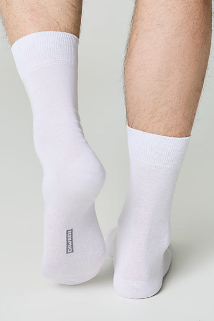 A pair of plain white mid-calf socks worn on a person's feet against a light grey background.