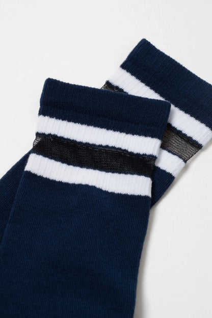 A pair of navy blue socks featuring two horizontal white stripes and a thin black semi-sheer stripe near the ribbed cuffs.
