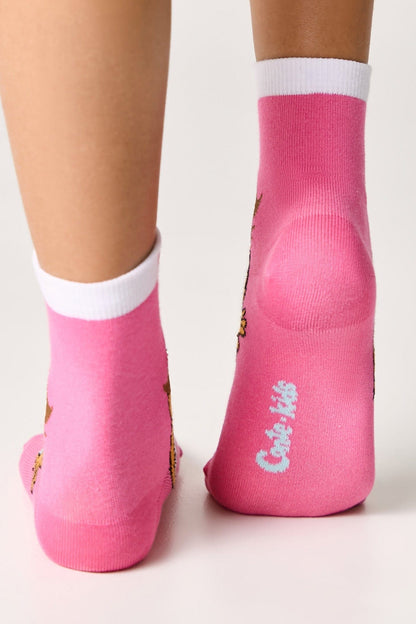 A pair of bright pink ankle socks featuring white cuffs and light blue text printed on the heel.