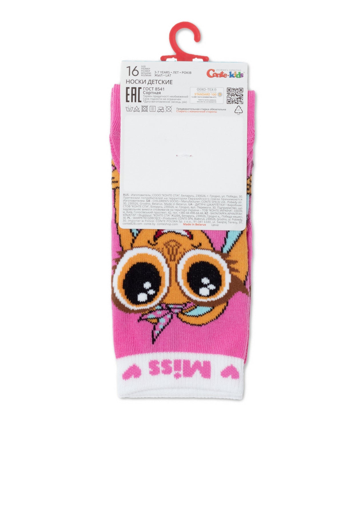 A pair of pink children's socks featuring a graphic of a yellow creature with large brown eyes and a small bow on a hanger with product information labels.