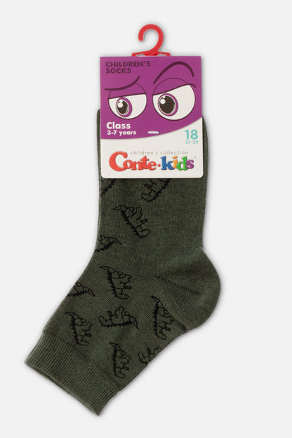 A single dark green children's sock with a repeating black dinosaur pattern, displayed with its original purple cardboard packaging.